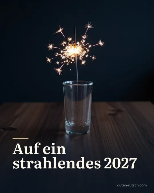 Brennende Wunderkerze in einer Glasvase vor dunklem Hintergrund, darauf der Gruß „Auf ein strahlendes 2027“