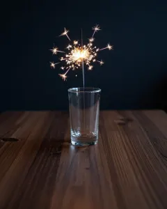 Brennende Wunderkerze in einer Glasvase vor dunklem Hintergrund
