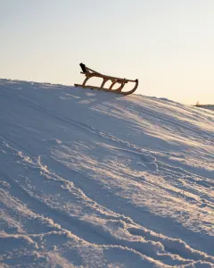 Holzschlitten oben auf einem verschneiten Hügel