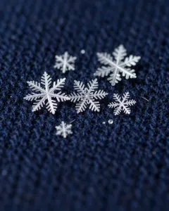 Schneeflocken in Nahaufnahme auf dunkelblauer Wolle